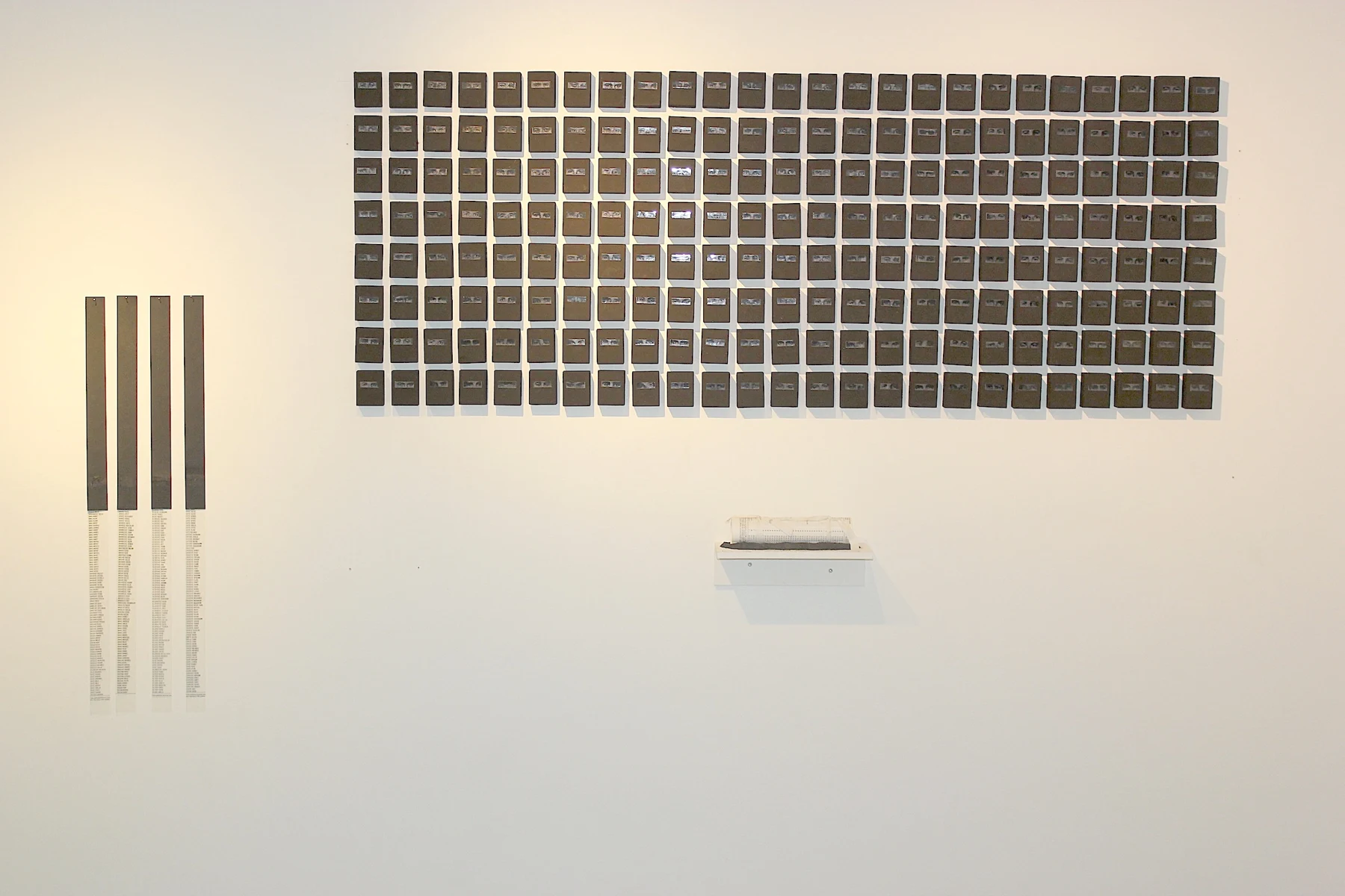 Installation de terres disposées en grille sur un mur de galerie